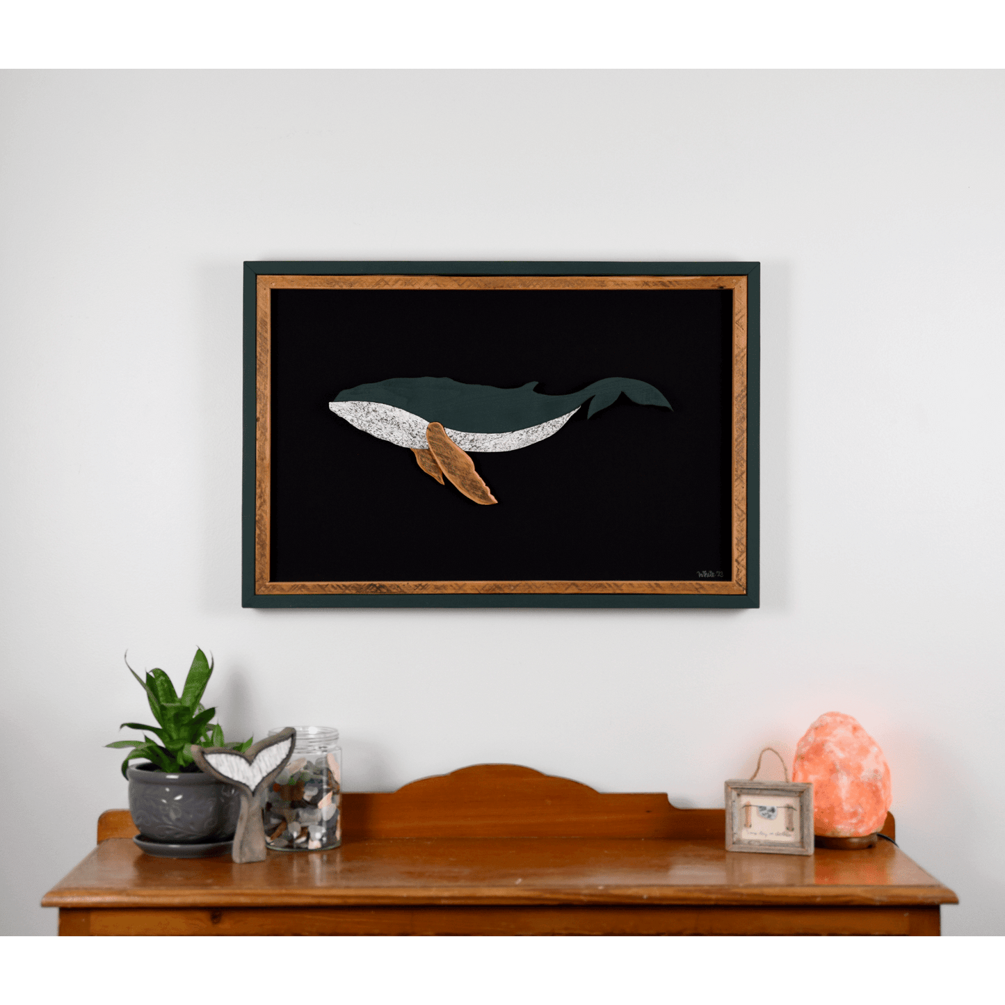 The Humpback showcases a humpback whale made from reclaimed wood and driftwood with green exterior frame, brown tone wood interior trim and fins, and a black canvas.