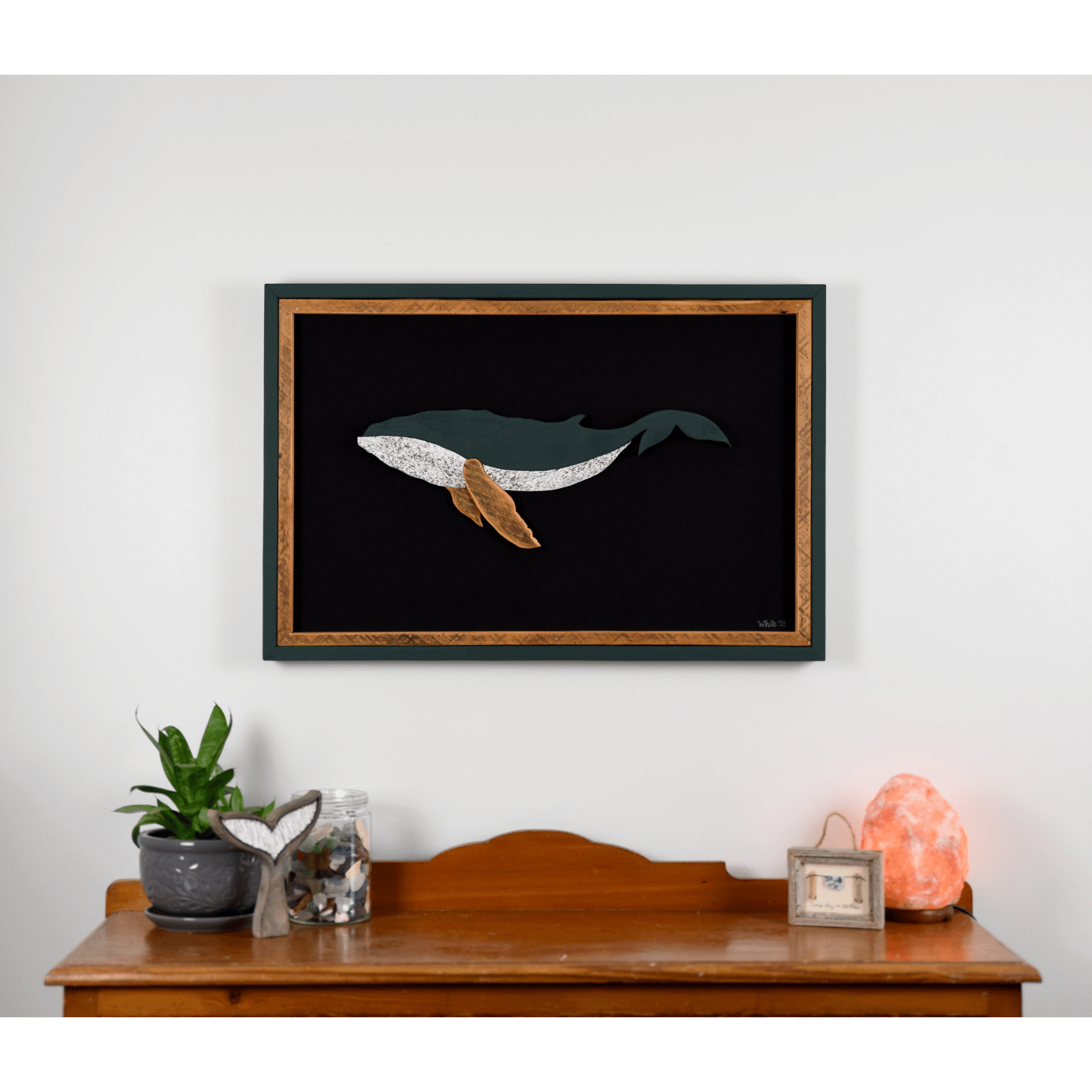 The Humpback showcases a humpback whale made from reclaimed wood and driftwood with green exterior frame, brown tone wood interior trim and fins, and a black canvas.