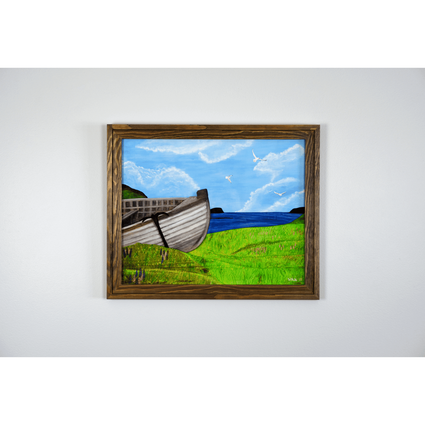 "New Beginnings" is a print featuring a wooden fishing boat that sits on a green Newfoundland shore with the ocean and seagulls in the background.