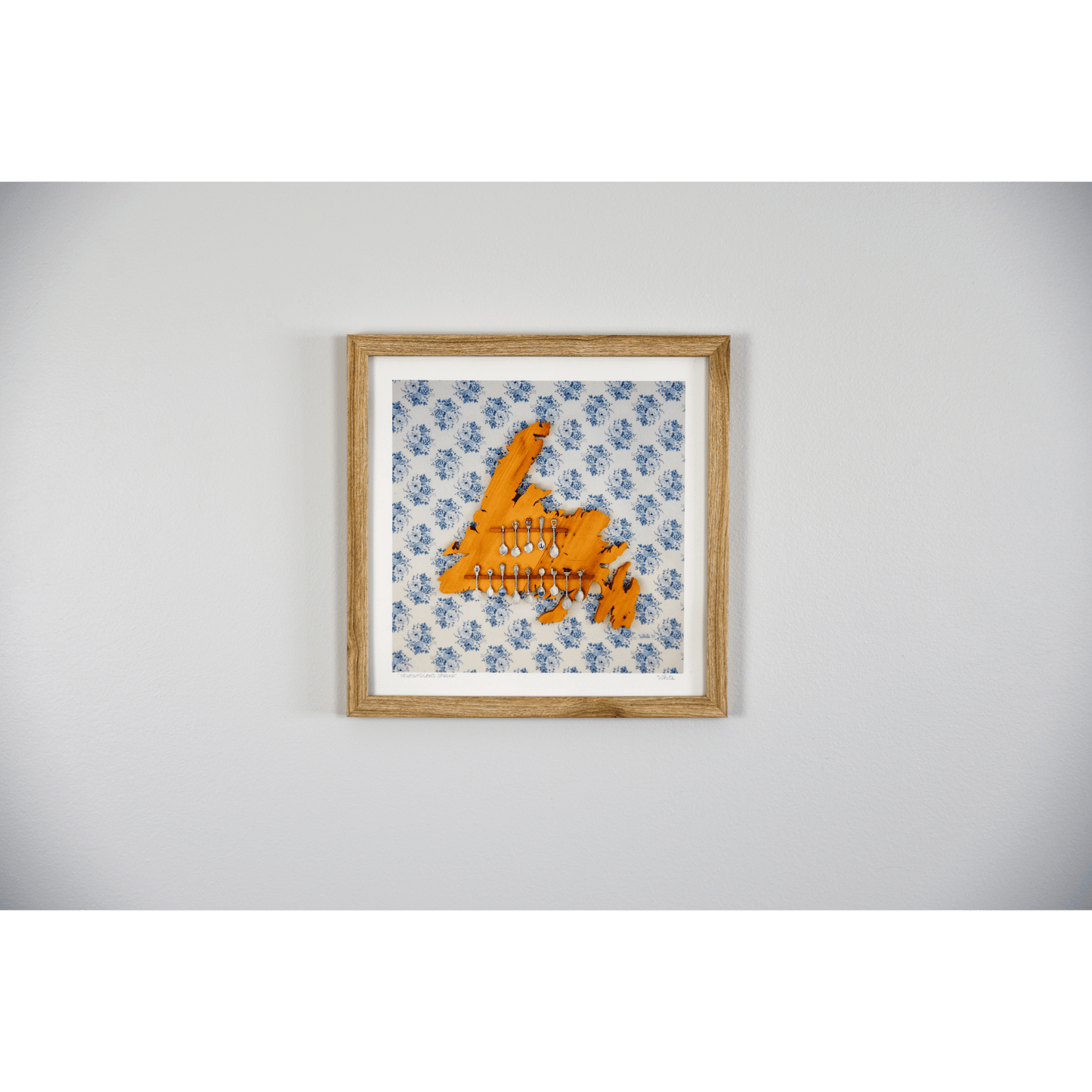 "Newfoundland Spoons" reproduction print showcases a wooden Newfoundland island spoon holder hanging on a flowery wallpapered wall.