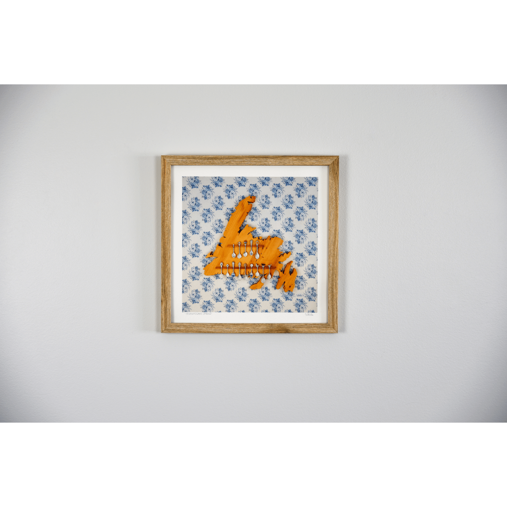 "Newfoundland Spoons" reproduction print showcases a wooden Newfoundland island spoon holder hanging on a flowery wallpapered wall.