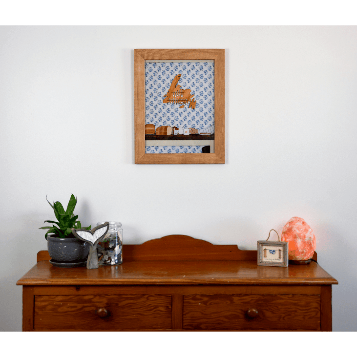 "Stealing the Healtap" print captures the warmth of a cozy family meal at Nan's, with bread, a mug, and a wooden spoon holder shaped like Newfoundland.