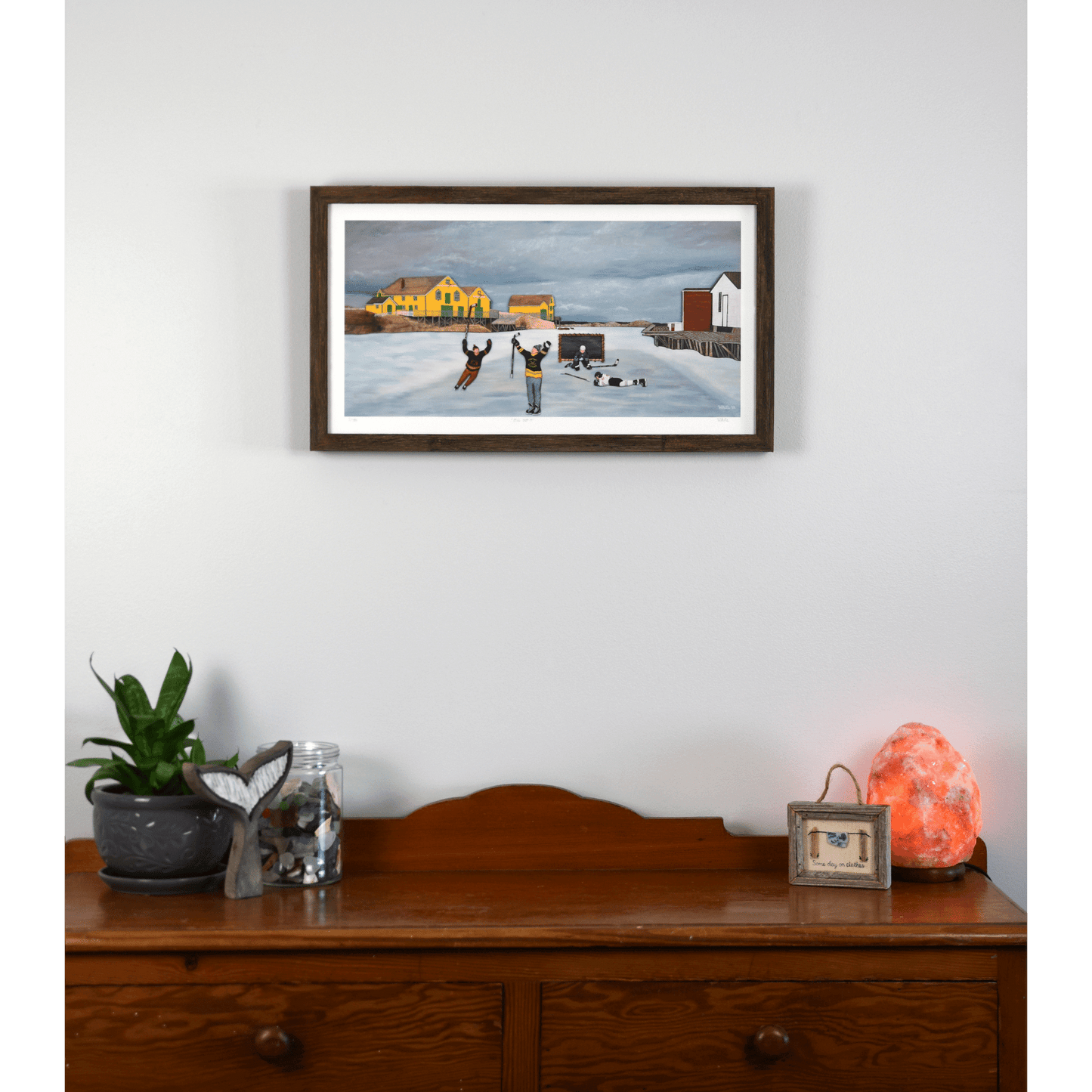 Experience the joy of winter in rural Newfoundland with "Still Got It" print. This reproduction features people playing hockey outside.