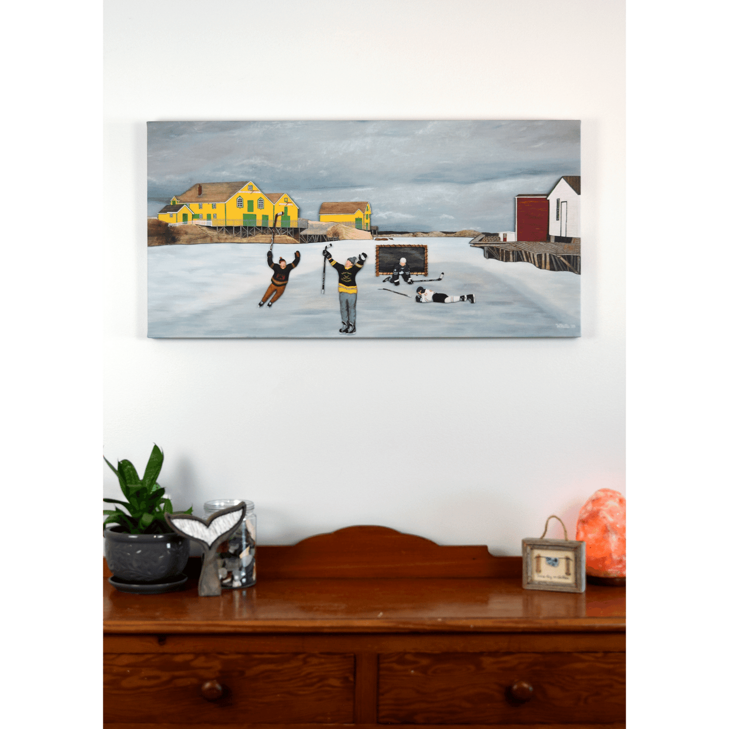 Experience the joy of winter in rural Newfoundland with "Still Got It" canvas print. This reproduction features people playing hockey outside.