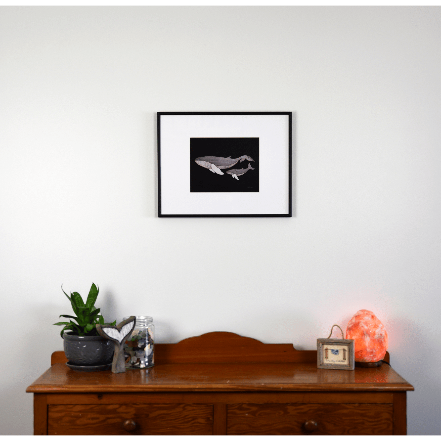 "The Mother" reproduction print depicts a mother whale and her calf swimming together. The pale wooden whales contrast against the navy blue background.
