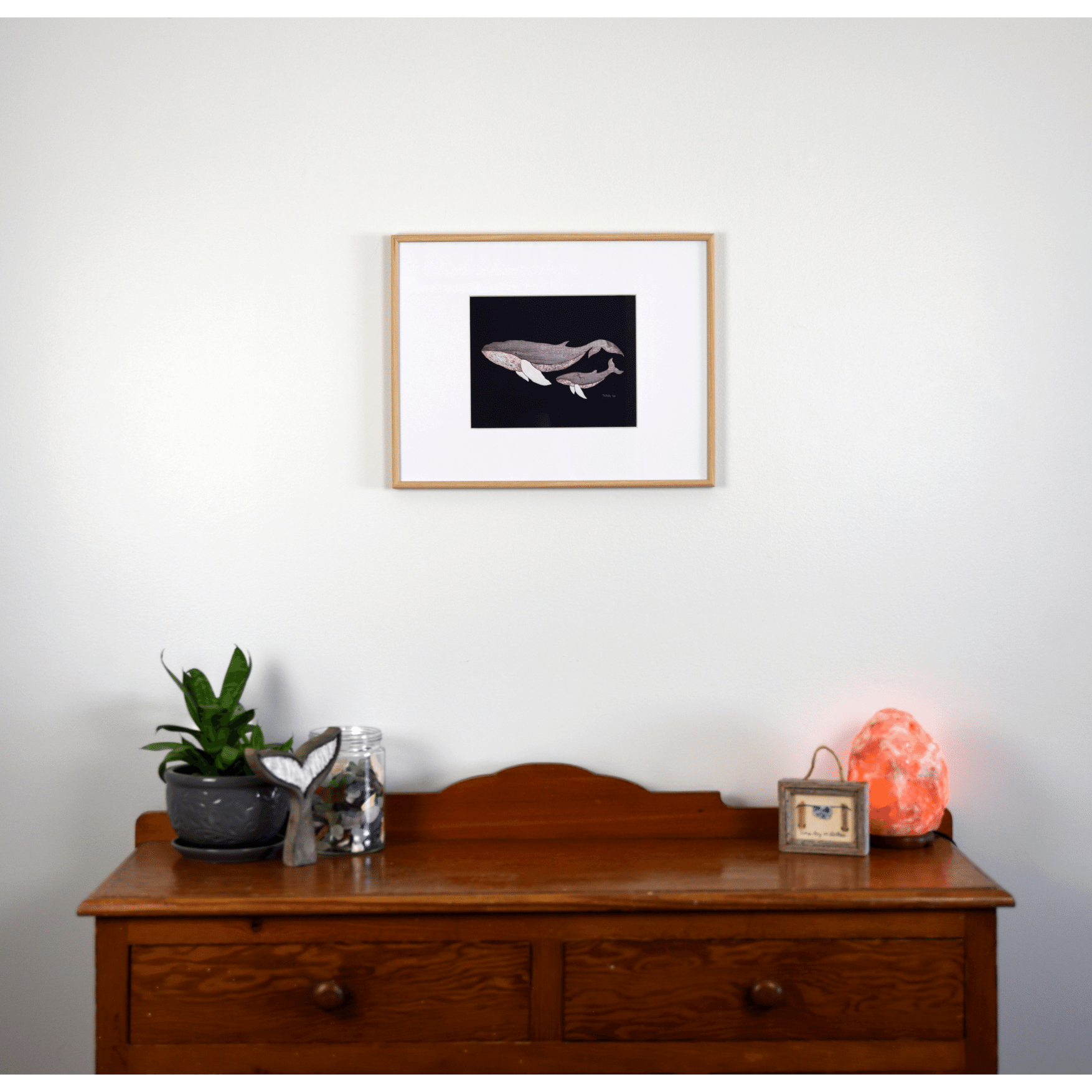 "The Mother" reproduction print depicts a mother whale and her calf swimming together. The pale wooden whales contrast against the navy blue background.