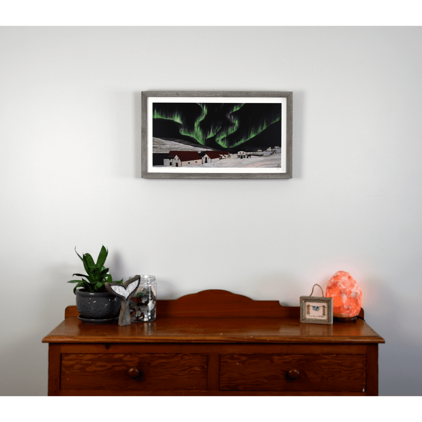 "The Northern Lights of Battle Harbour" reproduction print captures the vibrant colours of the aurora borealis over historic Battle Harbour during winter.