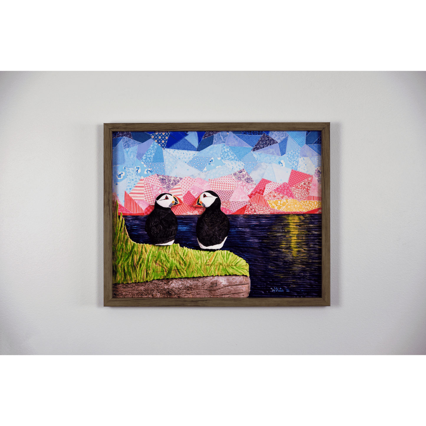 "The Perfect View" reproduction print showcases two puffins perched on a coastal rock, gazing lovingly at each other while enjoying a sunset over the ocean.