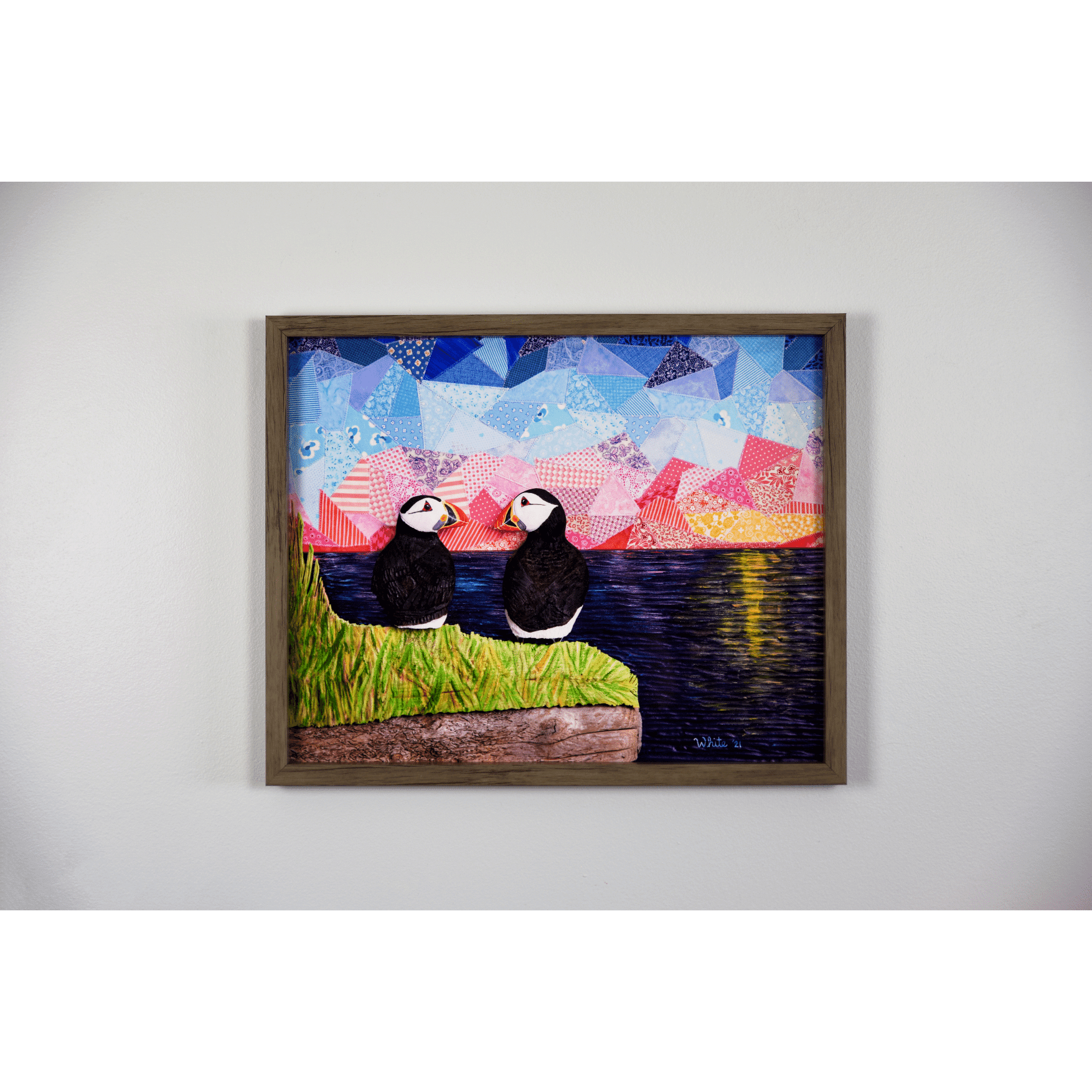 "The Perfect View" reproduction print showcases two puffins perched on a coastal rock, gazing lovingly at each other while enjoying a sunset over the ocean.