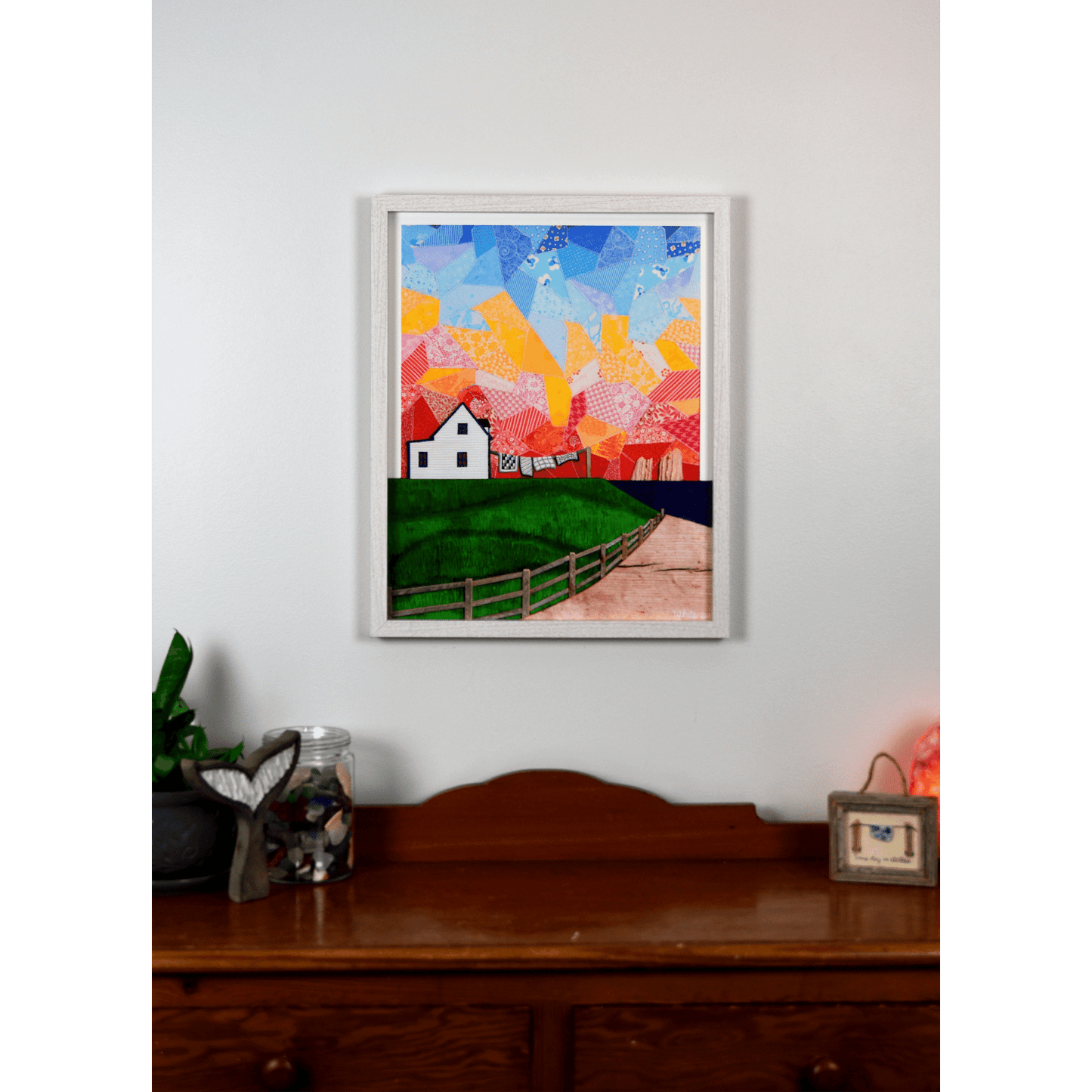 "Twillingate Sunrise" is a serene reproduction print showcasing a house against a patchwork pink and orange sky, with a green lawn and ocean in the foreground.