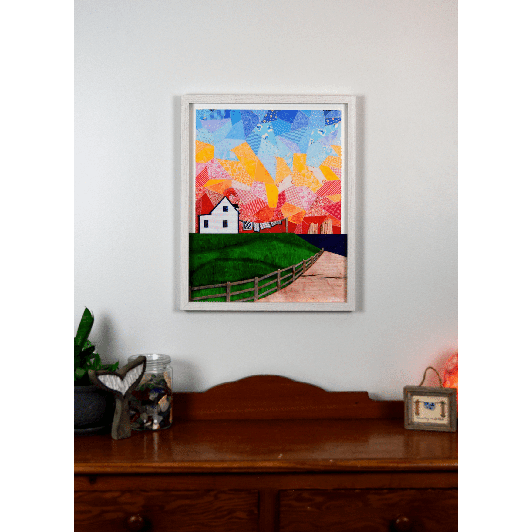 "Twillingate Sunrise" is a serene reproduction print showcasing a house against a patchwork pink and orange sky, with a green lawn and ocean in the foreground.
