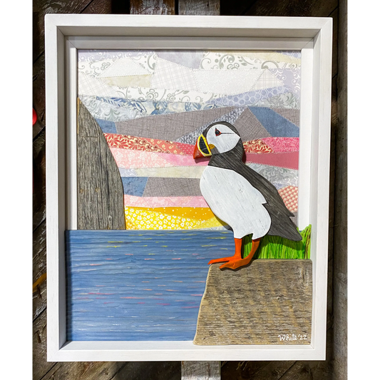 "Spring Views" is an original driftwood mixed-media art piece that captures a puffin standing on a rock over looking the water.