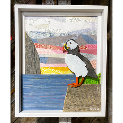 "Spring Views" is an original driftwood mixed-media art piece that captures a puffin standing on a rock over looking the water.