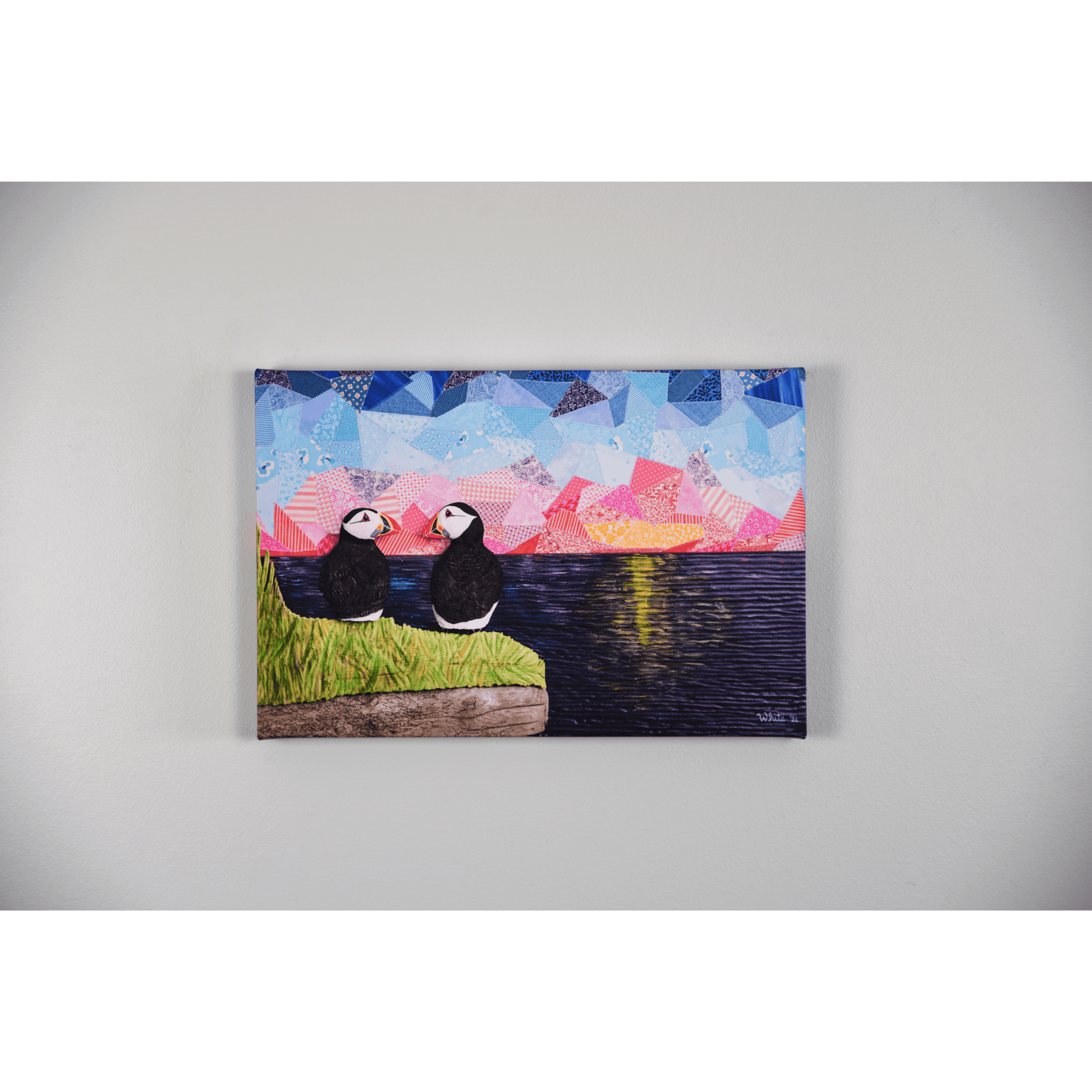 "The Perfect View" reproduction canvas showcases two puffins perched on a coastal rock, gazing lovingly at each other while enjoying a sunset over the ocean.