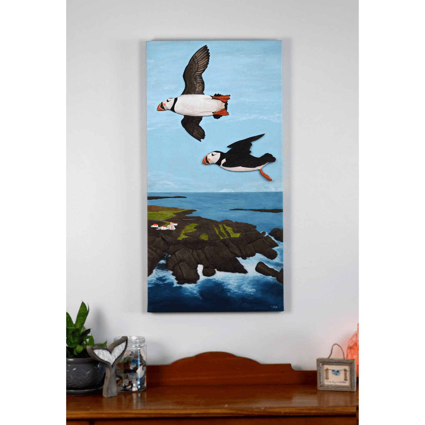 "Over the Cape" reproduction print showcases two puffins flying over the rugged Newfoundland coast.