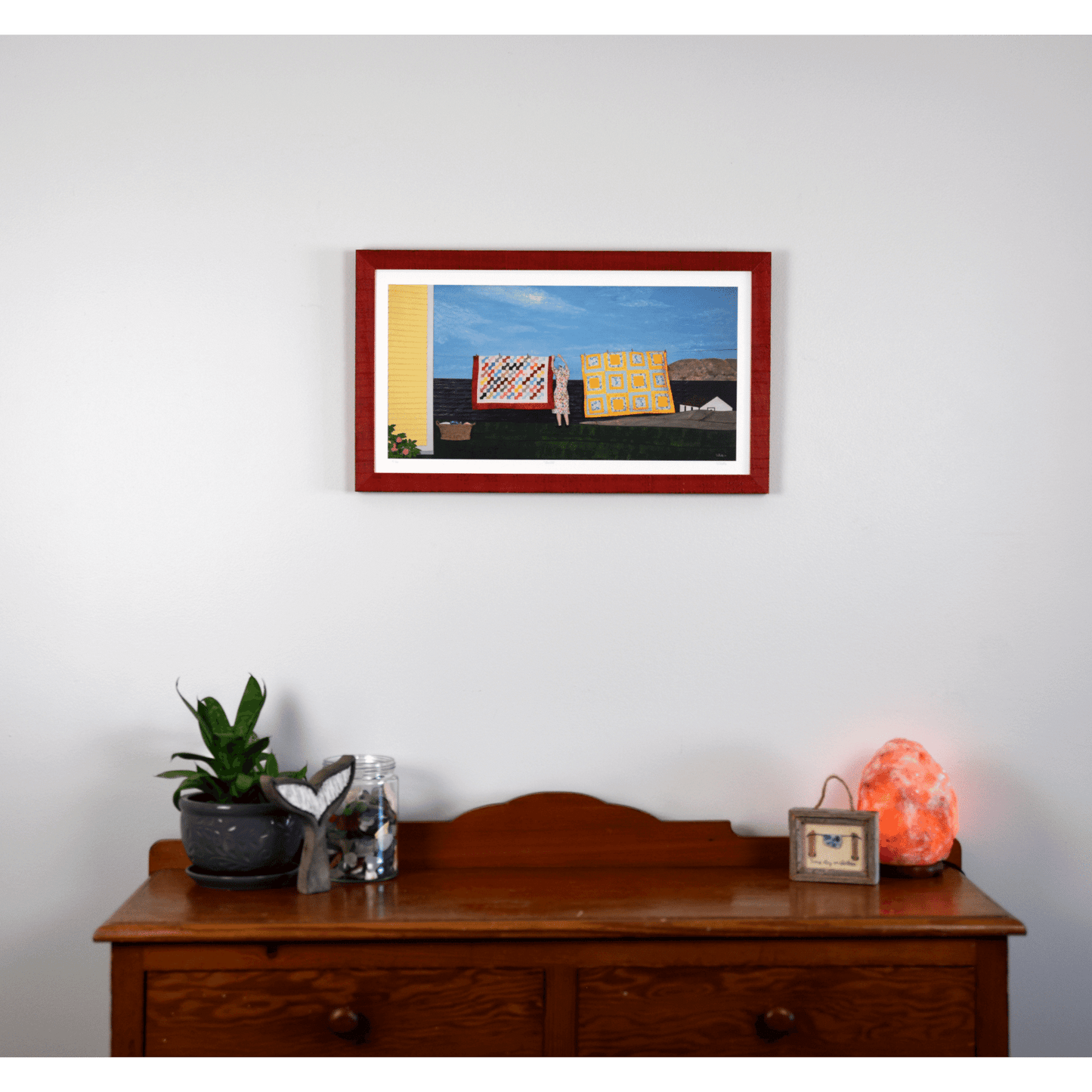 "Quilts" print features a woman in a yellow dress hanging quilts with the ocean and Twillingate coast in the background.