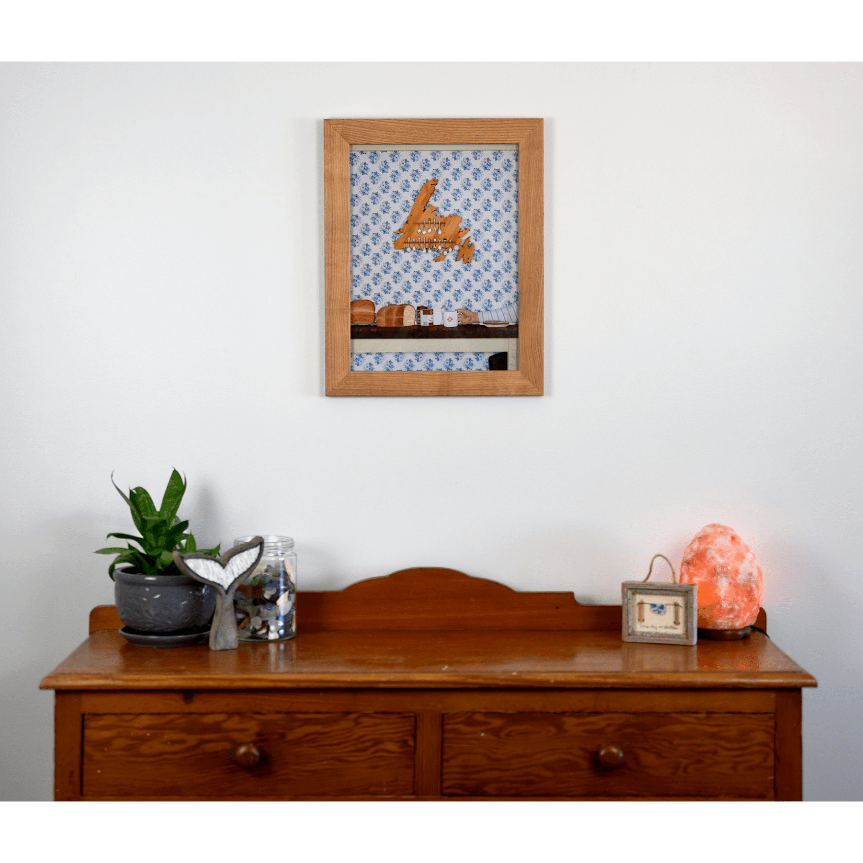 "Stealing the Healtap" print captures the warmth of a cozy family meal at Nan's, with bread, a mug, and a wooden spoon holder shaped like Newfoundland.