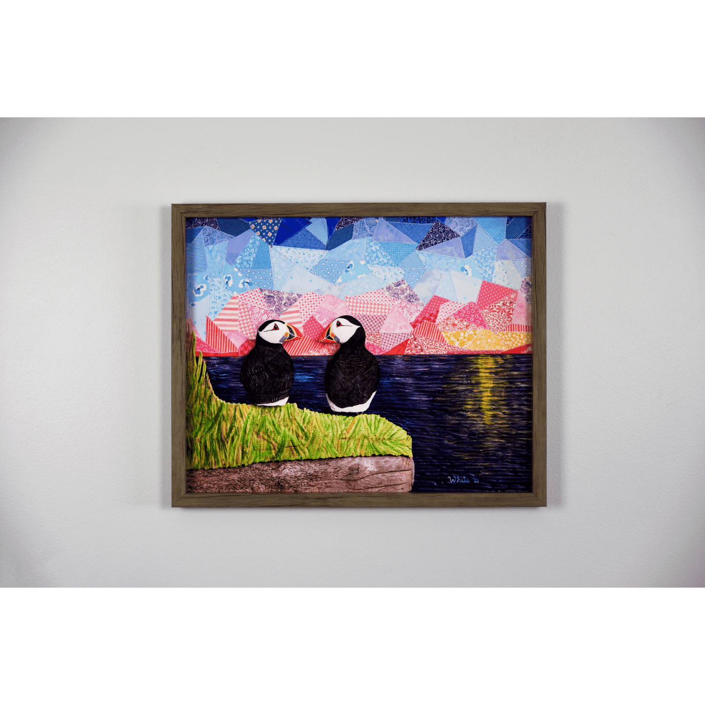  "The Perfect View" reproduction print showcases two puffins perched on a coastal rock, gazing lovingly at each other while enjoying a sunset over the ocean.